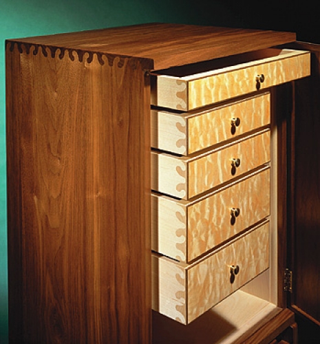 Closeup of Jewellery Cabinet in American black walnut with book matched veneer front and maple inlays. Featuring wave joint pattern. 46H x 15W x 12D